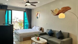 A modern bedroom with a bed, a sofa, a coffee table, and a ceiling fan.