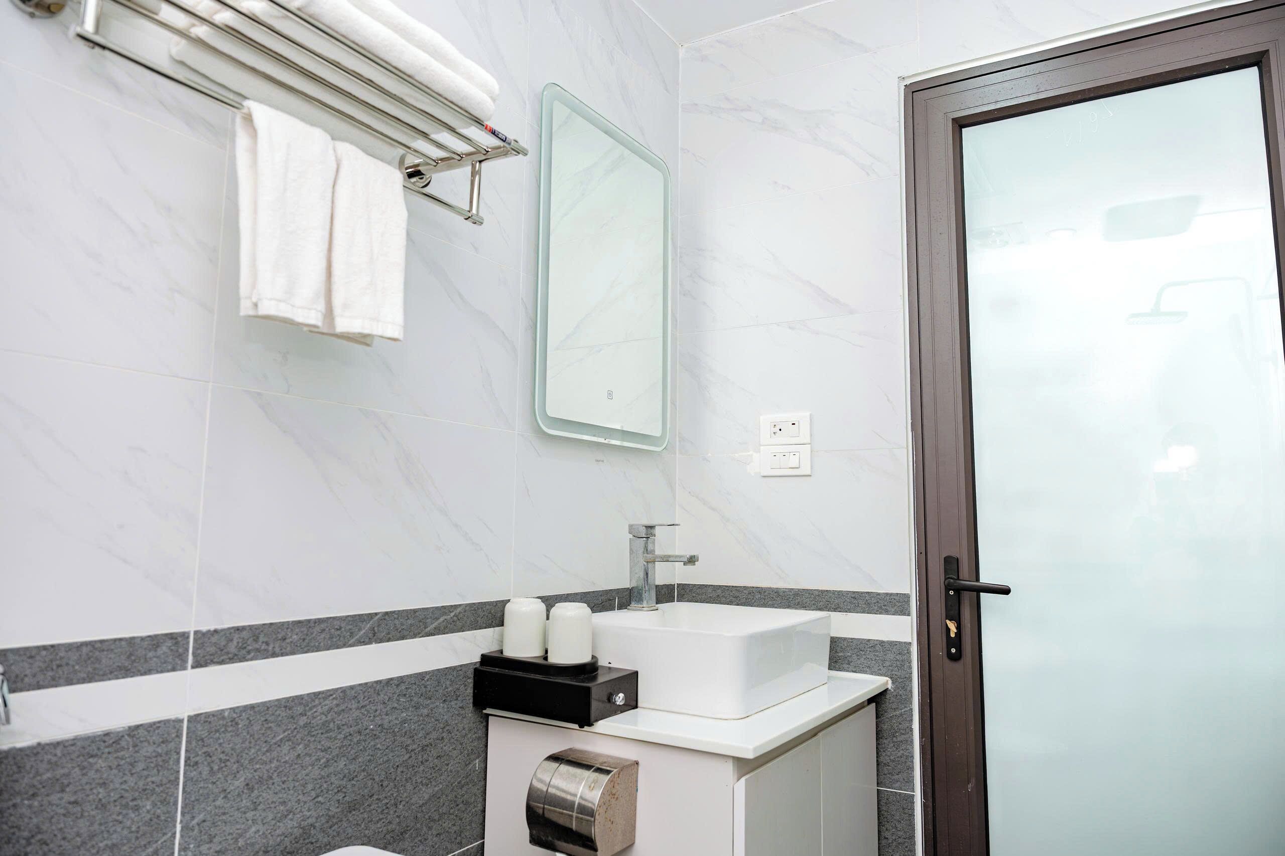 A bathroom with a white sink, mirror, towel rack, and a door with a frosted glass panel.