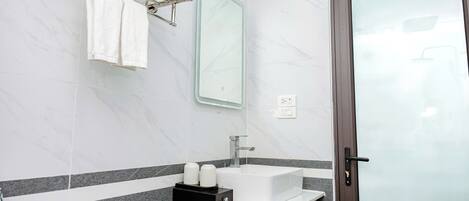 A bathroom with a white sink, mirror, towel rack, and a door with a frosted glass panel.