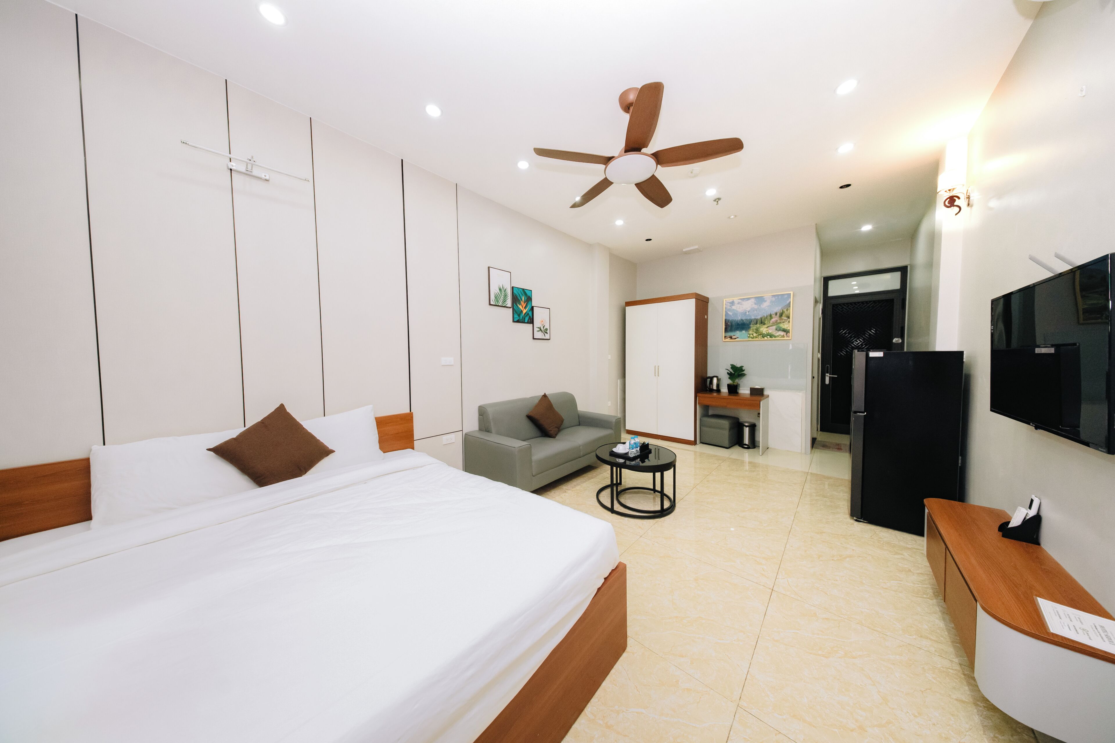 Une chambre d’hôtel équipée d’un lit, d’un canapé, d’un bureau, d’une télévision et d’un ventilateur de plafond.