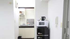 Una cocina compacta con microondas, un refrigerador pequeño y un lavamanos.