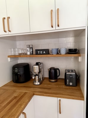 A kitchen with white cabinets, a coffee maker, a toaster, and a tea box on the countertop.