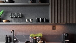 A modern kitchen with a dark backsplash, a sink, a coffee machine, and decorative items like candles and potted plants. - Hideaway Herdla 1 – unique and luxurious cabin 15 m above the sea near Bergen (Herdla)