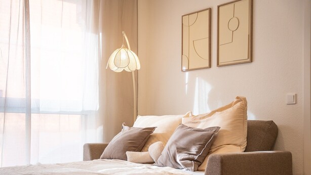 A bedroom with a bed, pillows, a lamp, and two framed artworks on the wall. - Apartment 'Riversidesuite Tübingen' with Shared Terrace, Shared Garden and Wi-Fi (Tübingen)