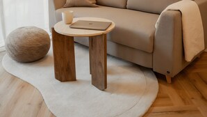 A modern living room with a sofa, a round wooden table, a lamp, and two framed abstract artworks on the wall. - Apartment 'Riversidesuite Tübingen' with Shared Terrace, Shared Garden and Wi-Fi (Tübingen)