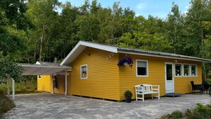 A yellow building with a covered patio area, a small seating area with a bench, and a door labeled "ERD". - 5 Star Holiday Home in Aakirkeby (Akirkeby)