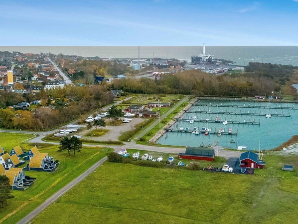 Un port de plaisance avec des bateaux amarrés, un phare en arrière-plan et un bâtiment rouge au premier plan.