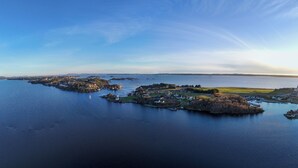 Vue aérienne d’une ville côtière, avec un pont imposant, plusieurs petites îles et une vaste étendue d’eau.