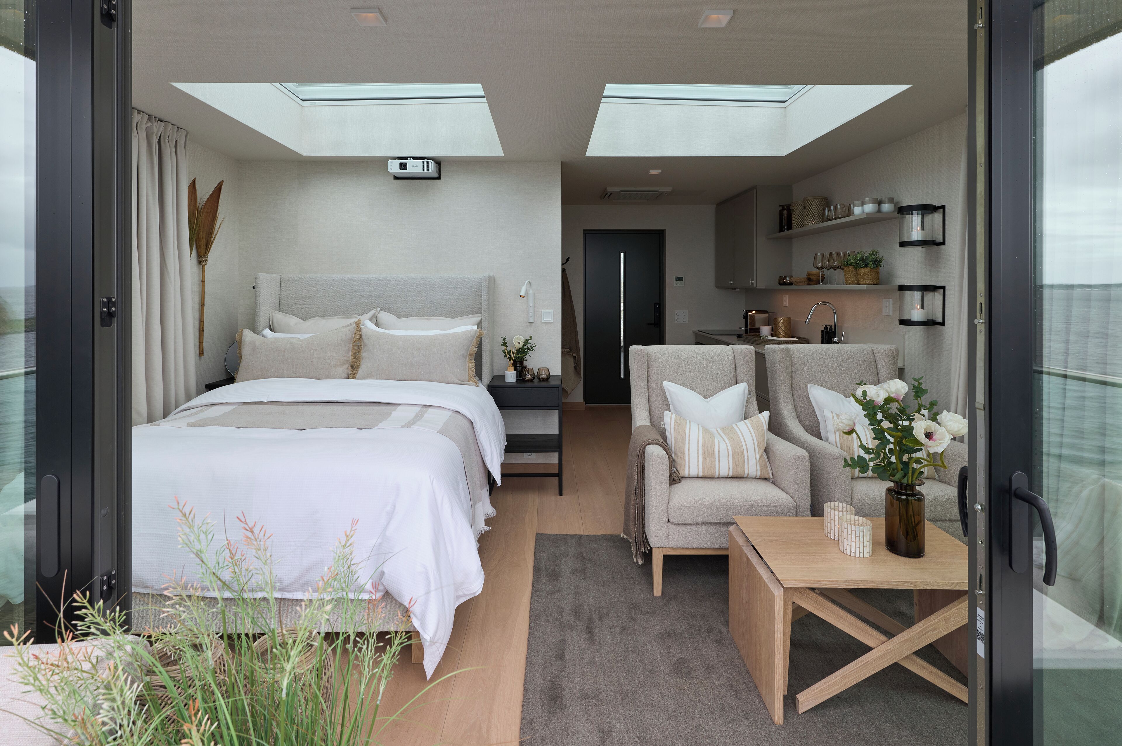 Un dormitorio moderno con una cama grande, un sofá y una pequeña mesa con un florero.