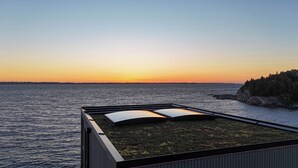 Une terrasse sur le toit offrant une vue sur la mer et un magnifique coucher de soleil.