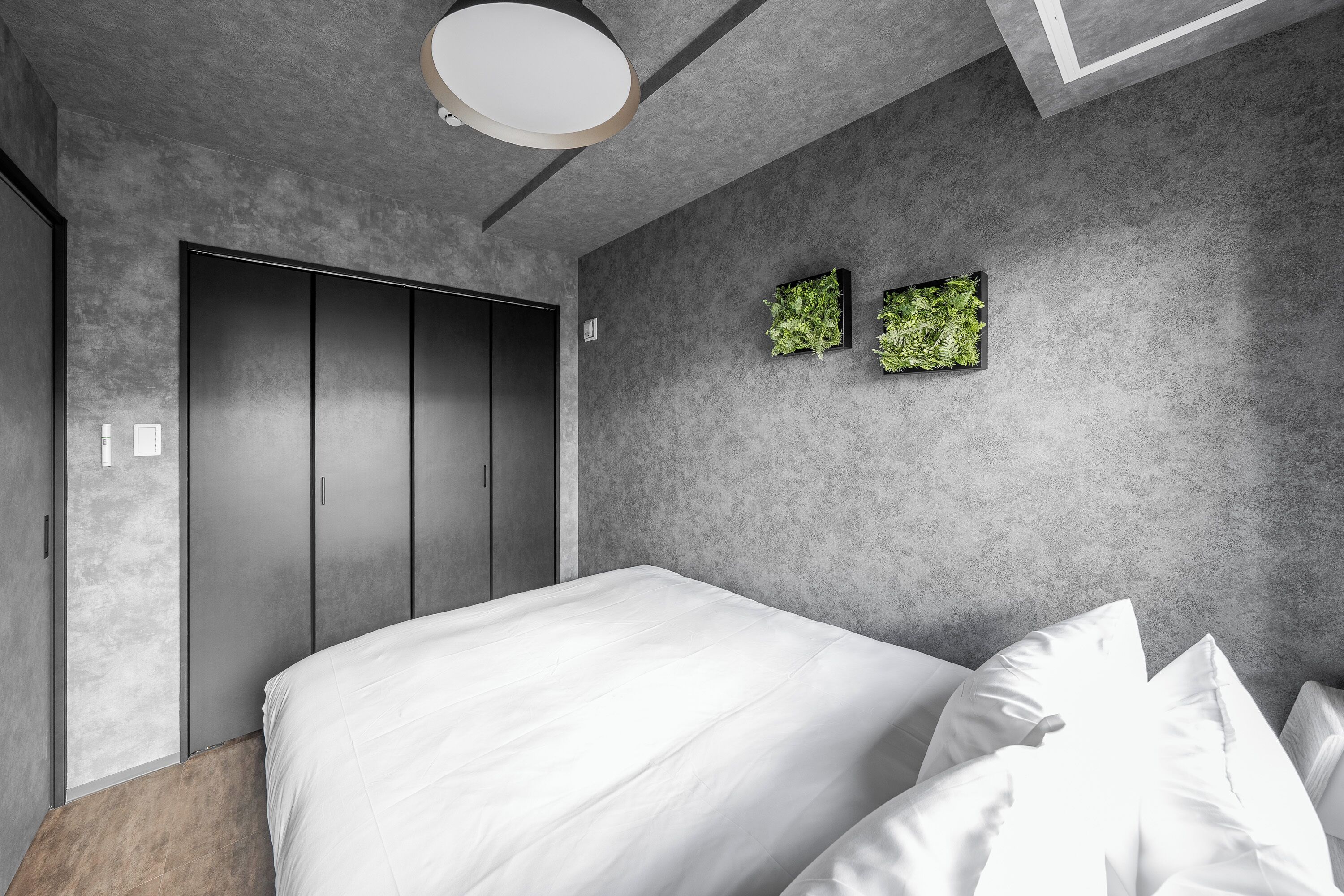 A modern bedroom with a large bed, grey walls, and a wardrobe.