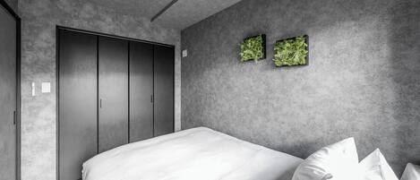 A modern bedroom with a large bed, grey walls, and a wardrobe.