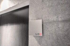 Une porte d’ascenseur métallique sur laquelle est affiché le numéro « 102 ».
