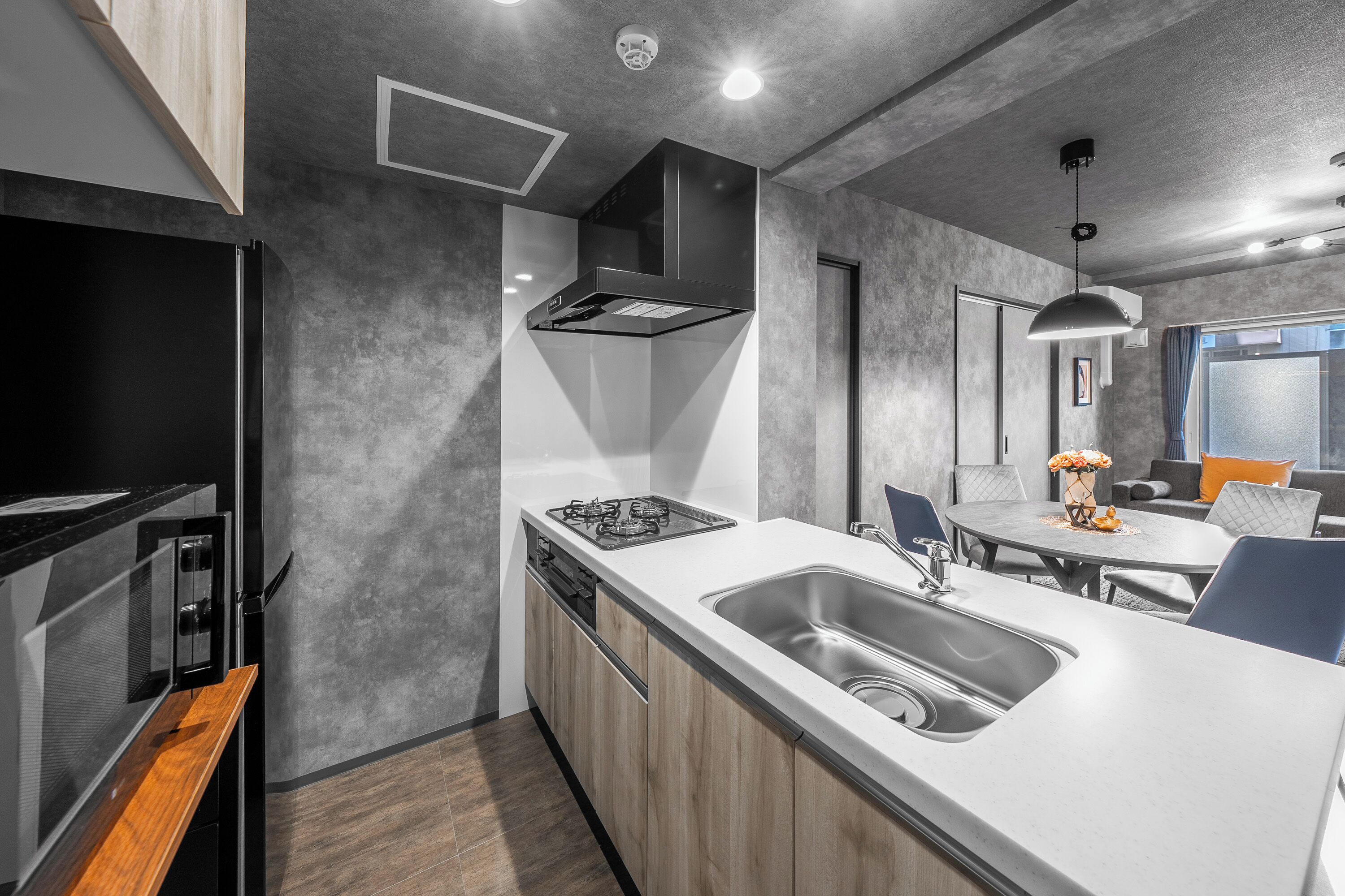 A modern kitchen with a built-in oven, a large sink, and a dining area with a table and chairs.