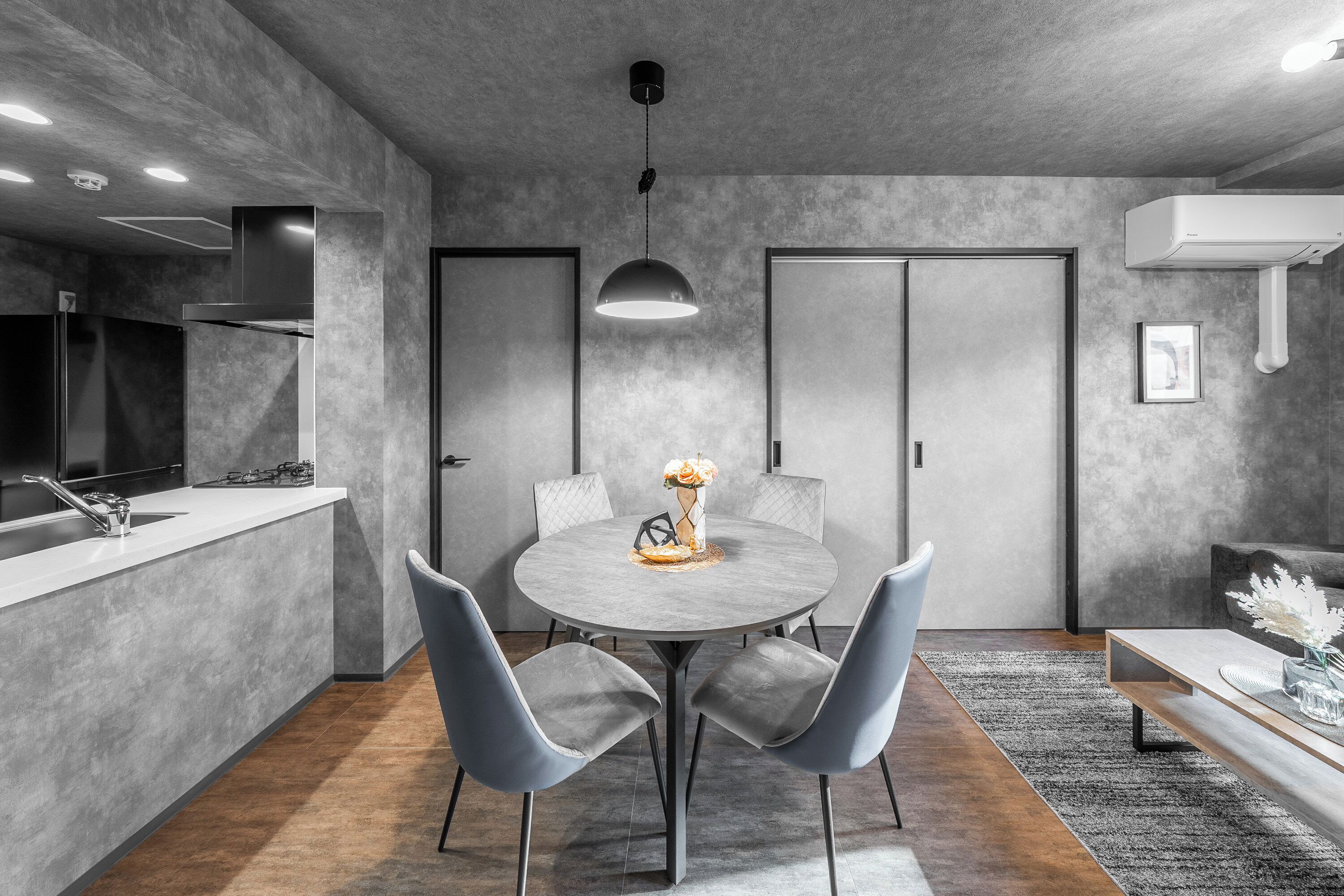 A modern kitchen with a built-in stove, a sink, and a dining area with a round table and chairs.