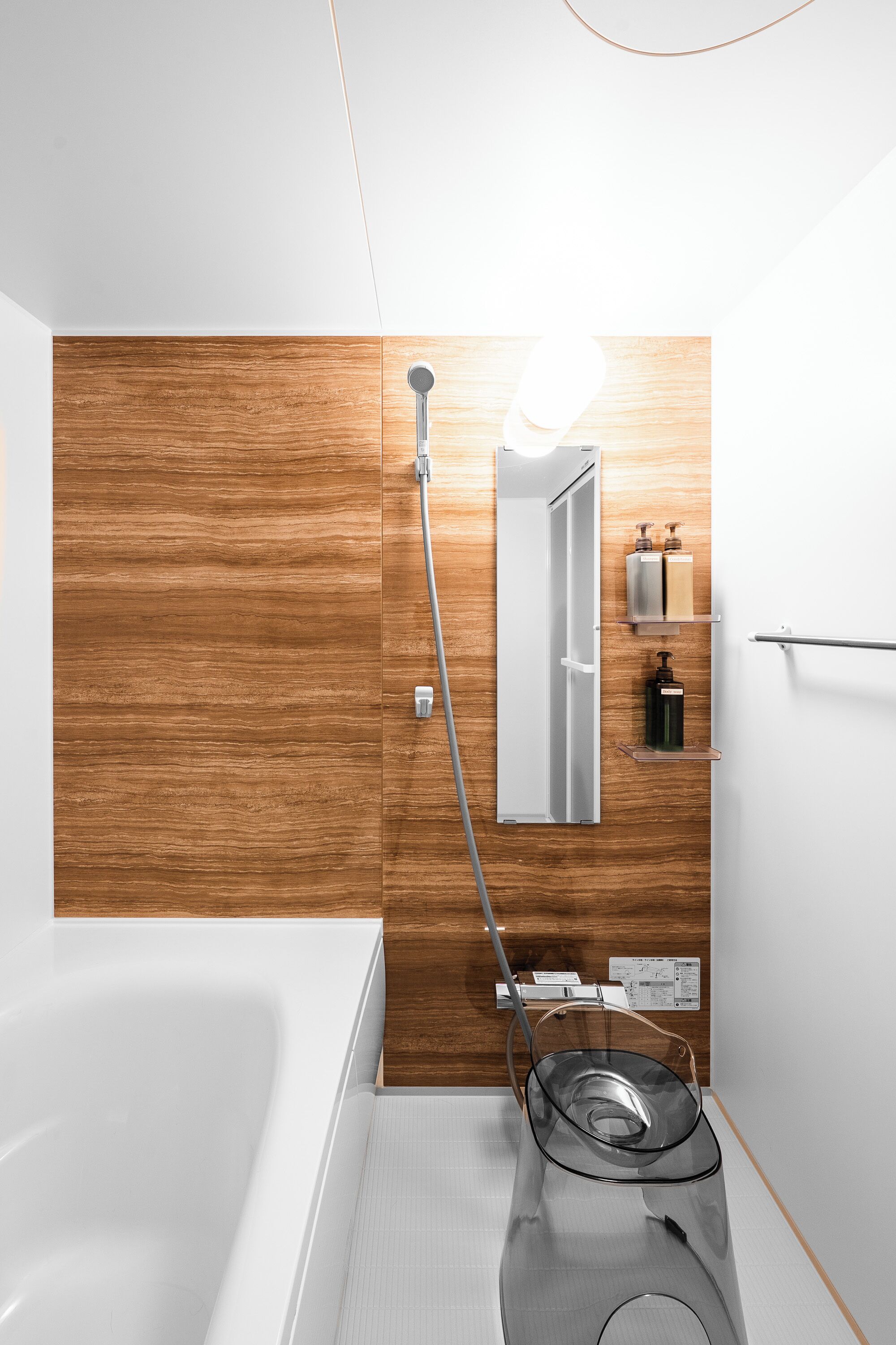 Une salle de bain moderne avec un mur en bois, une baignoire blanche, une cabine de douche en verre et un miroir.