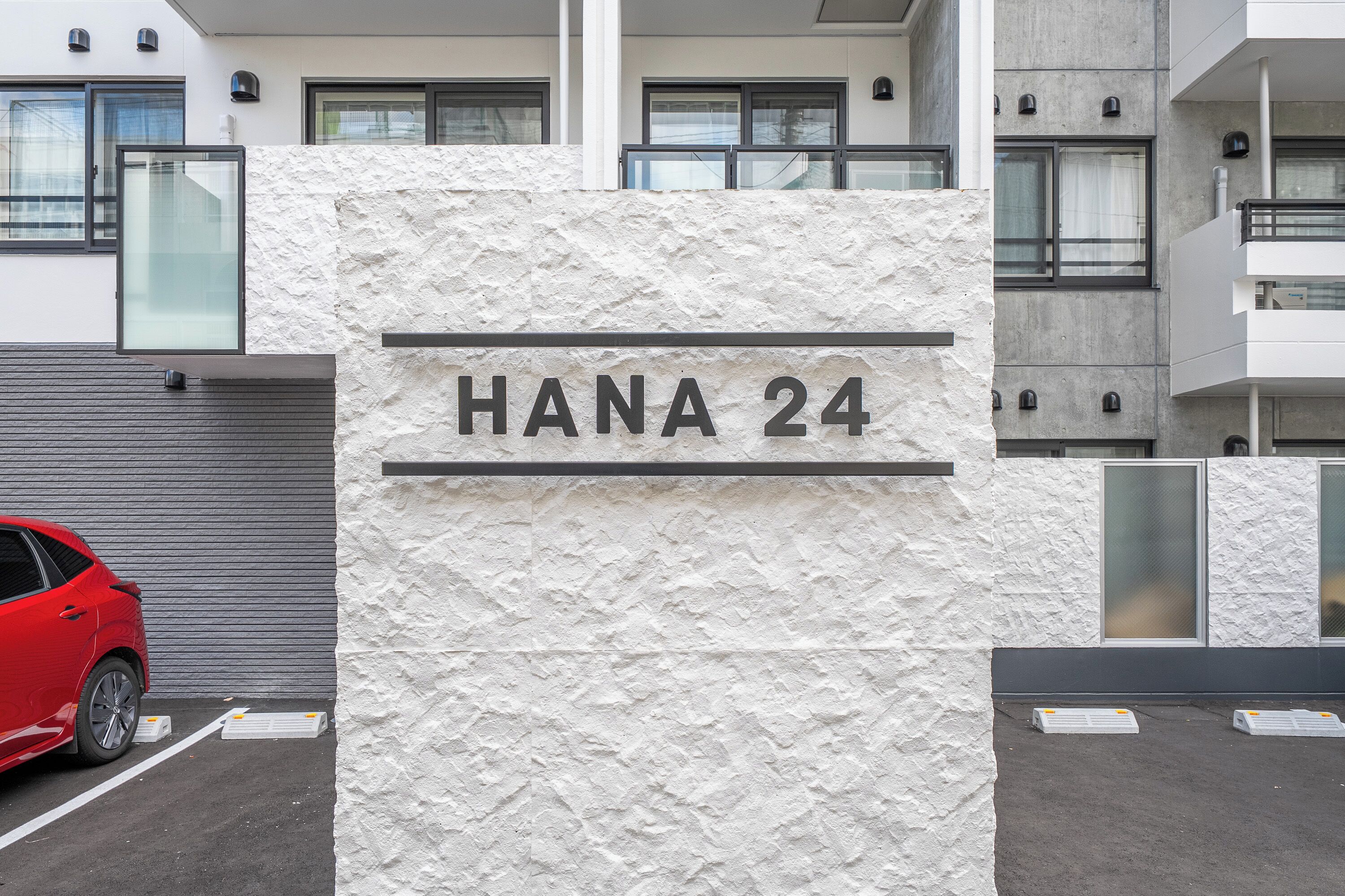 A building with a textured facade and a sign reading "HANA 24".