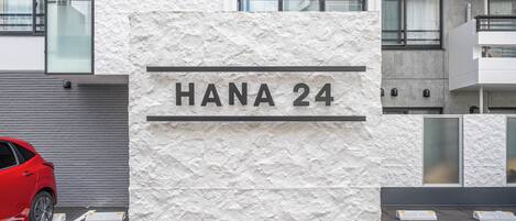 A building with a textured facade and a sign reading "HANA 24".