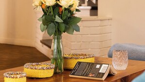 A wooden table with a vase of flowers, a book, and decorative baskets. - United House (Nairobi)