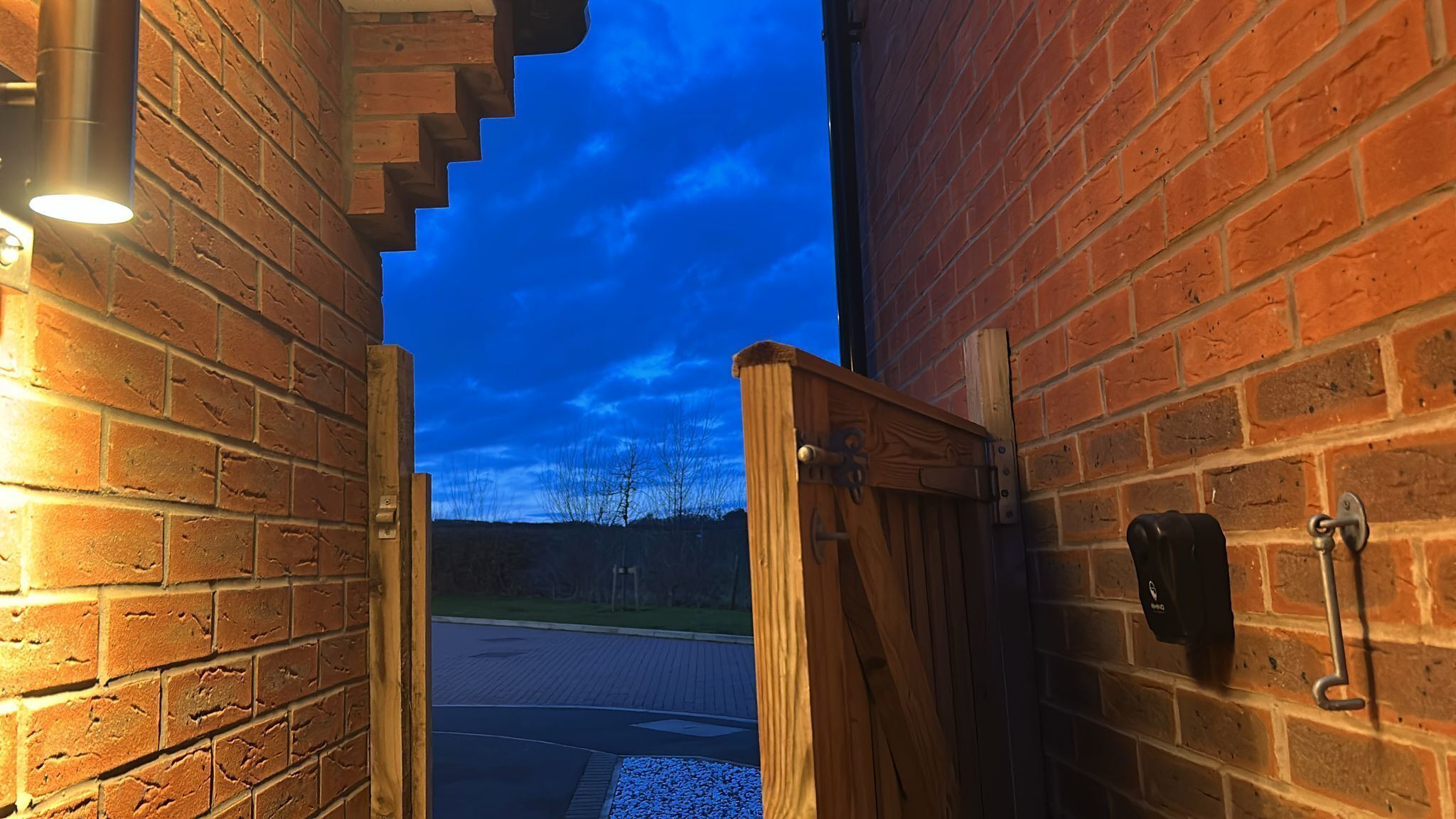 A brick building with a wooden gate, a metal handle, and a keypad lock.