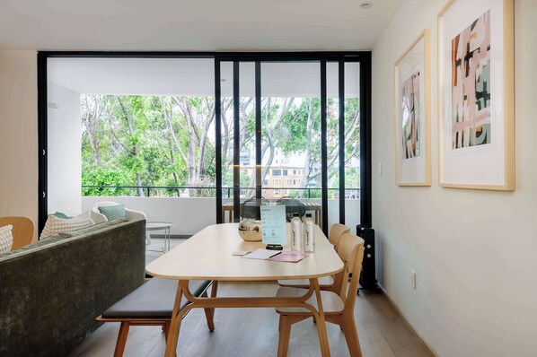 A modern room with a balcony, a dining table, and a sofa.
