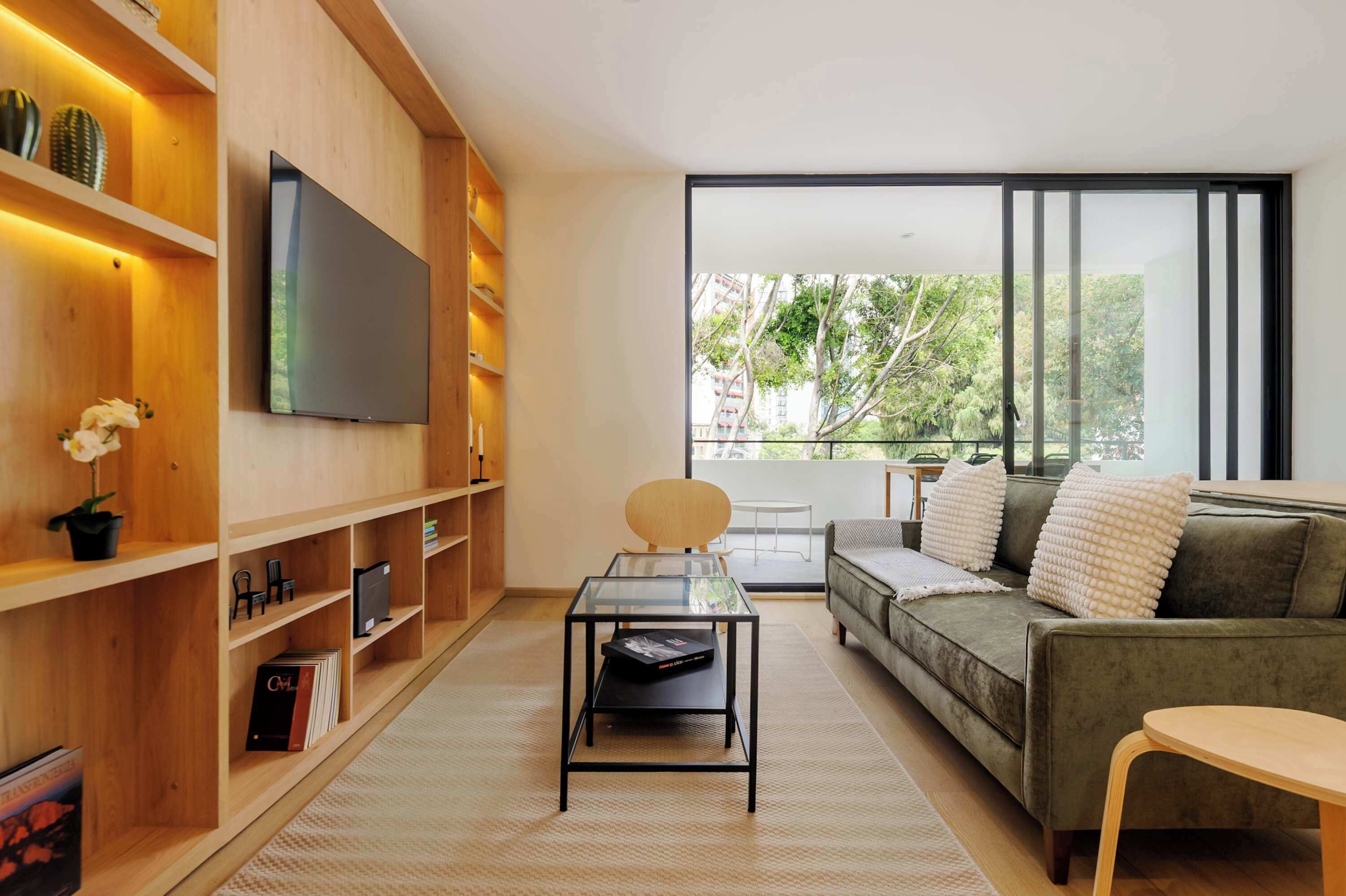 A modern living room with a sofa, a coffee table, and a TV mounted on a wooden wall.