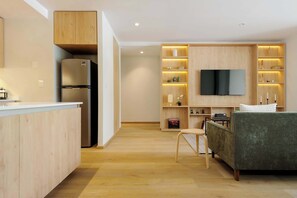 A modern kitchen with a built-in refrigerator, wooden cabinetry, and a flat-screen TV mounted on the wall.