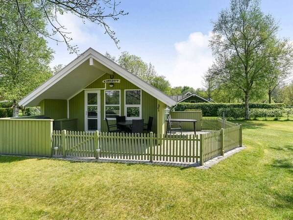 A small, single-story building with a green exterior and a white picket fence. - 5 Star Holiday Home in Grindsted (Grindsted)
