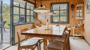Un intérieur en bois avec une grande table à manger, des chaises et des luminaires suspendus.