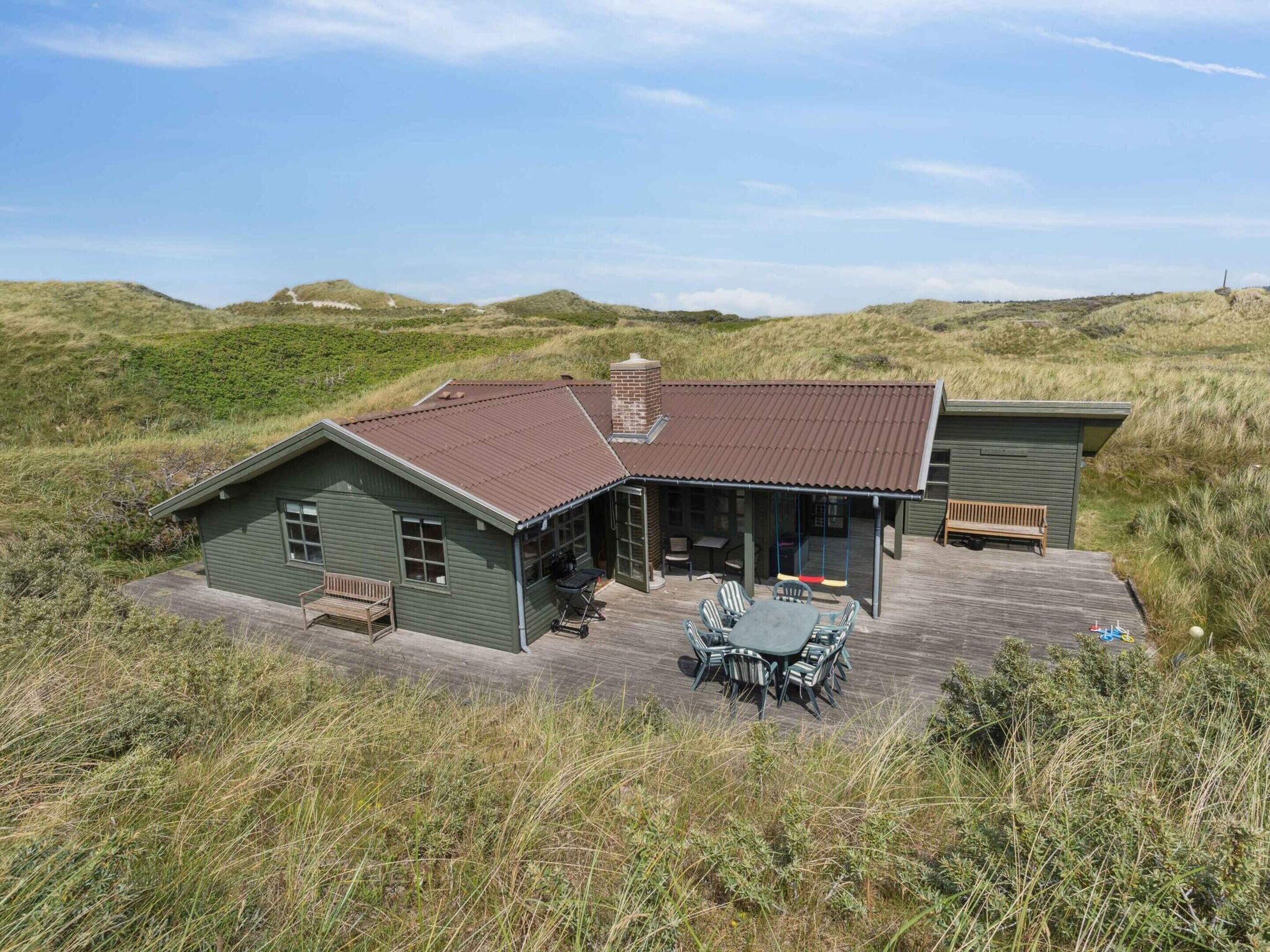 Een huis met een terras, een eethoek en een schommel.