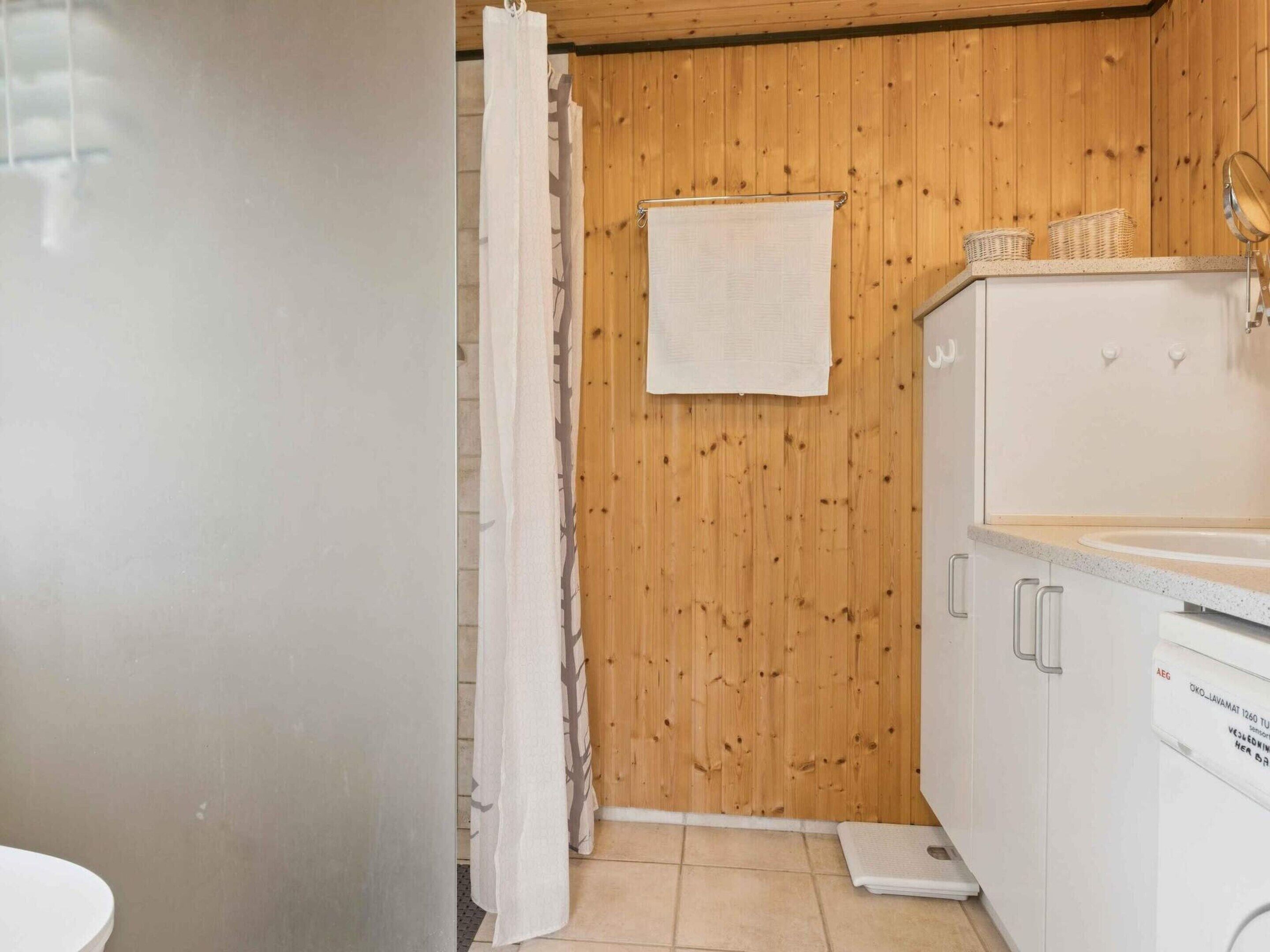 A bathroom with wooden walls, a white sink, and a towel hanging on the wall.
