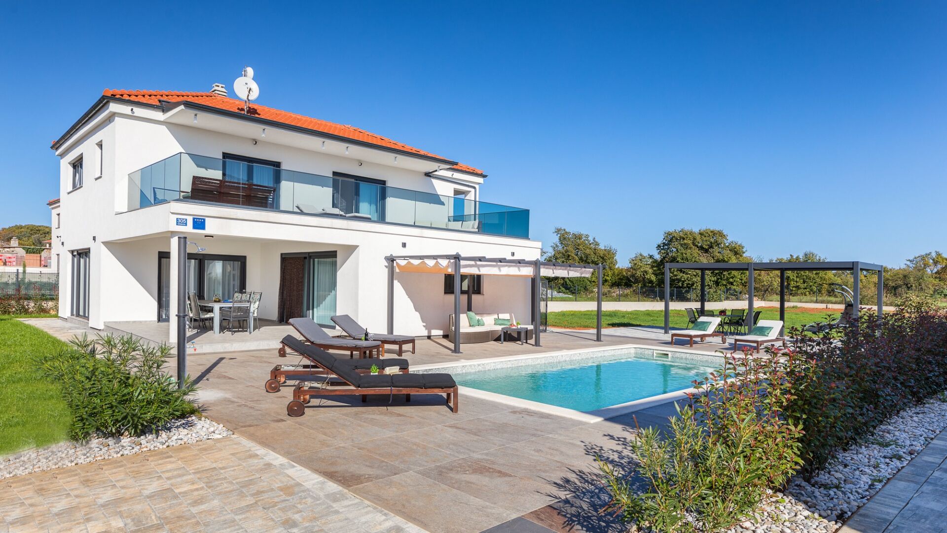 A modern two-story house with a swimming pool, outdoor seating, and a covered patio area.