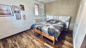 Een slaapkamer met een houten bed, een radiator en een raam met zonwering.