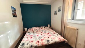 Ein Schlafzimmer mit einem Bett, einem Fenster und einer Heizung.