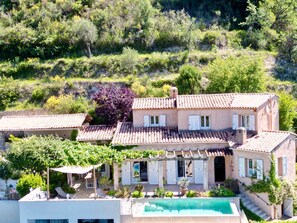 A villa with a swimming pool, multiple terraces, and a garden.