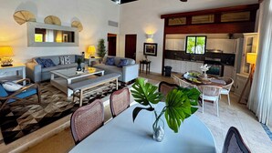 A spacious living area with a dining table, sofas, and a kitchen in the background.