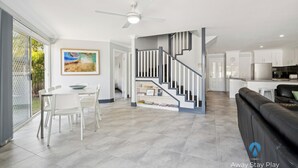 Un salon moderne comprenant un coin repas, un escalier et une cuisine.