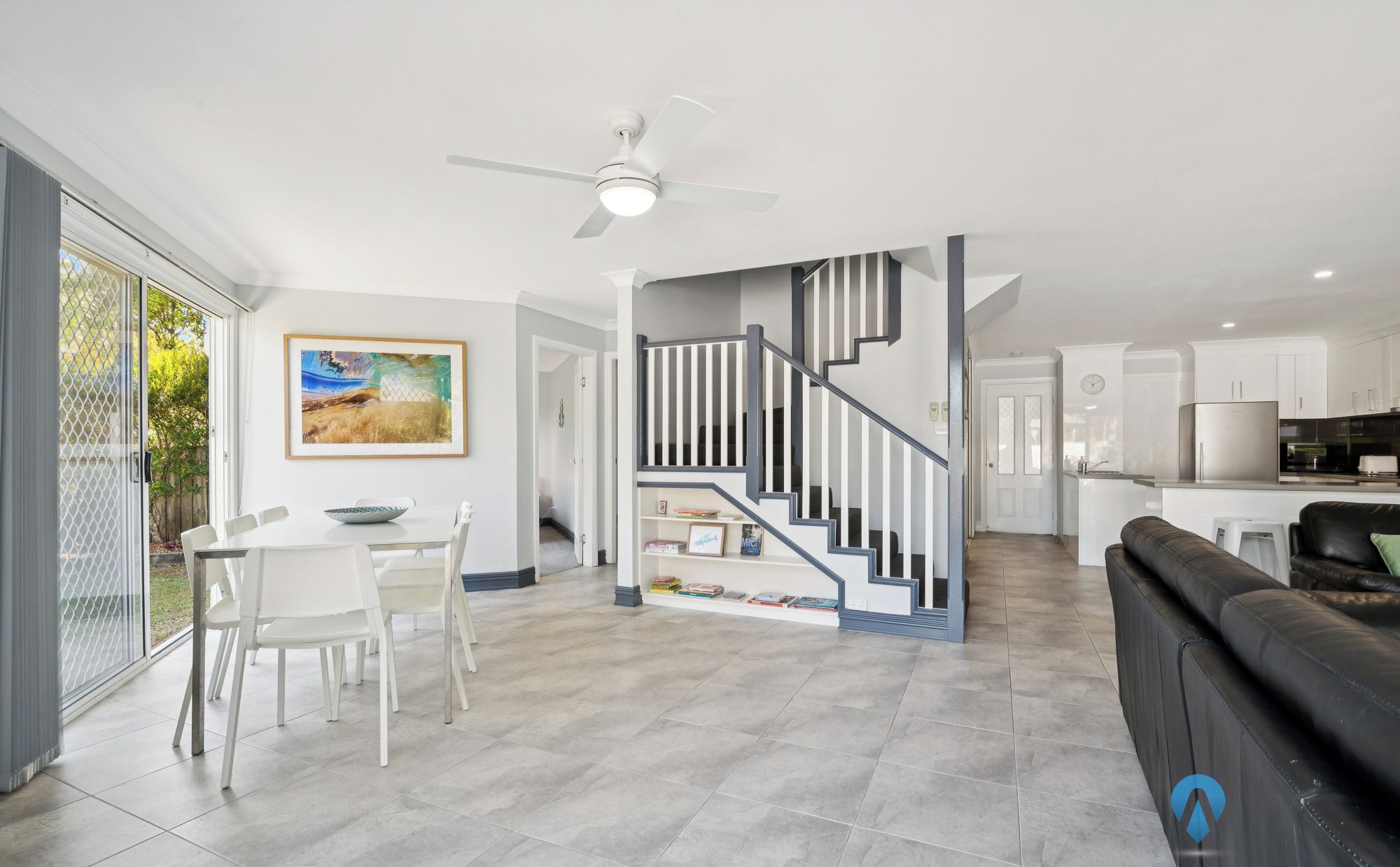 A modern living room with a dining area, a staircase, and a kitchen.