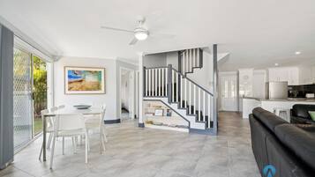A modern living room with a dining area, a staircase, and a kitchen.