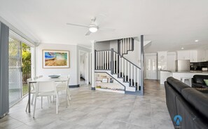 Un salon moderne comprenant un coin repas, un escalier et une cuisine.