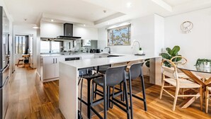 Una cucina moderna con una grande isola, sgabelli da bar e un tavolo da pranzo con sedie.
