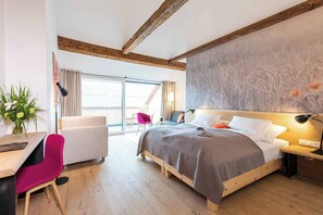 Une chambre d’hôtel moderne avec un plafond en bois, un grand lit avec une literie grise, un bureau avec une chaise et une grande fenêtre avec des rideaux.