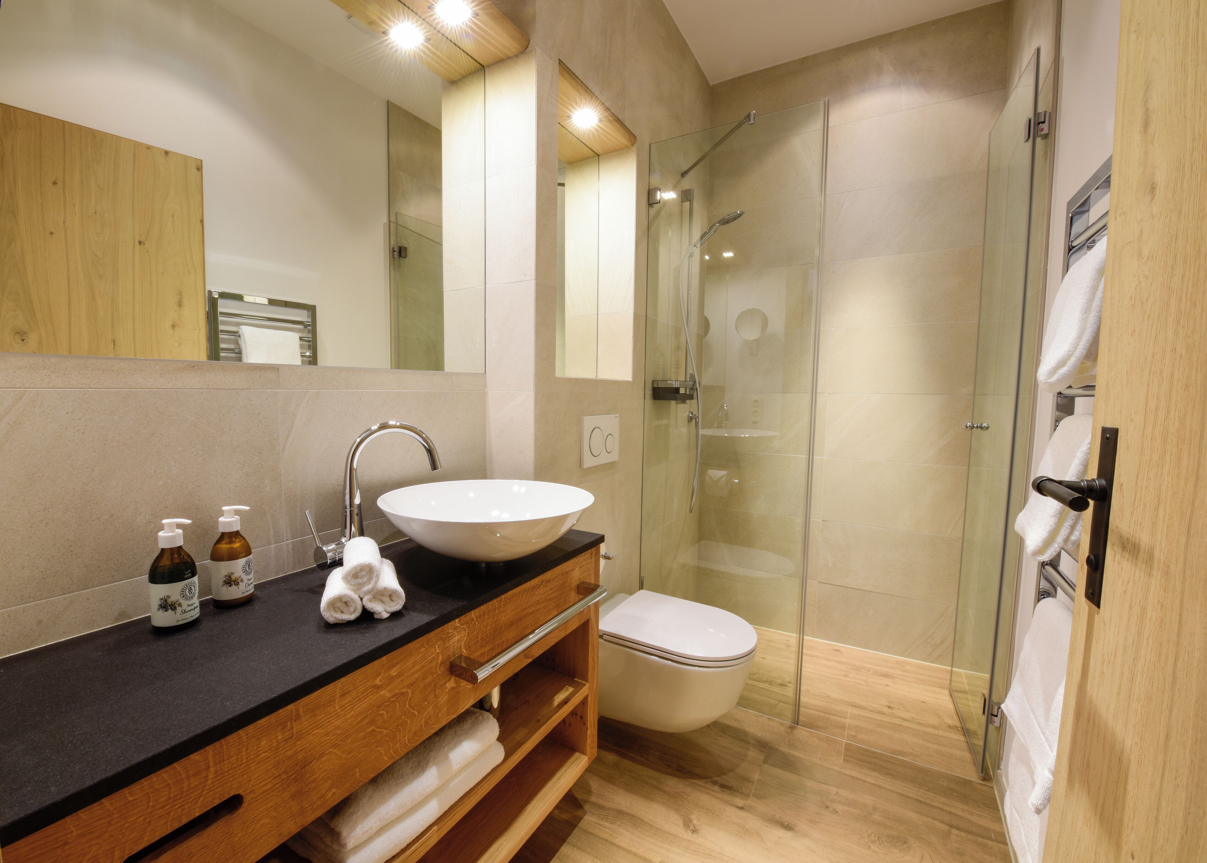 Ein modernes Badezimmer mit einem großen Waschbecken, einem Spiegel und einer Duschkabine aus Glas.