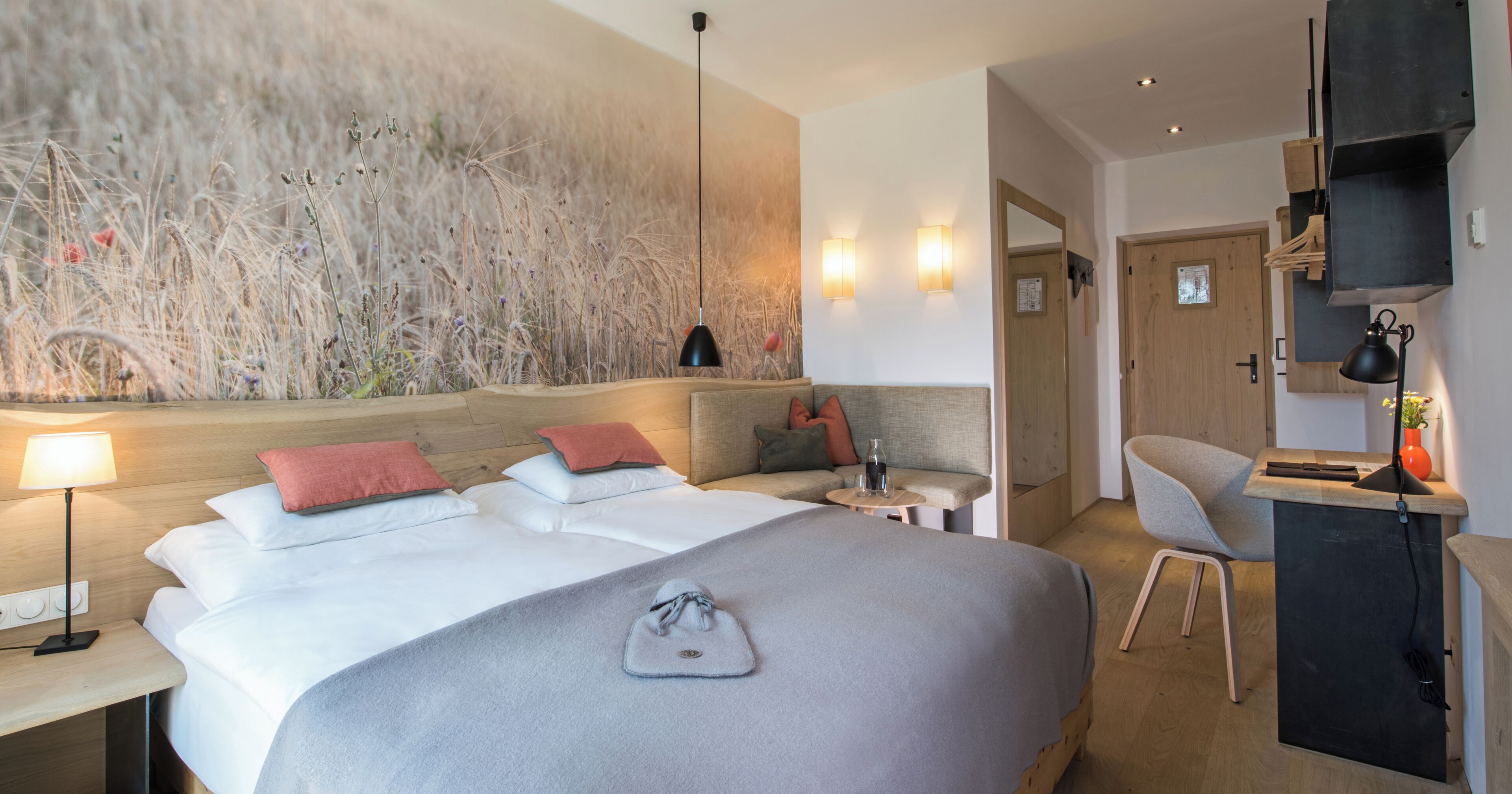 Una habitación de hotel moderna con una cama grande, mesitas de noche, un escritorio y un televisor montado en la pared.