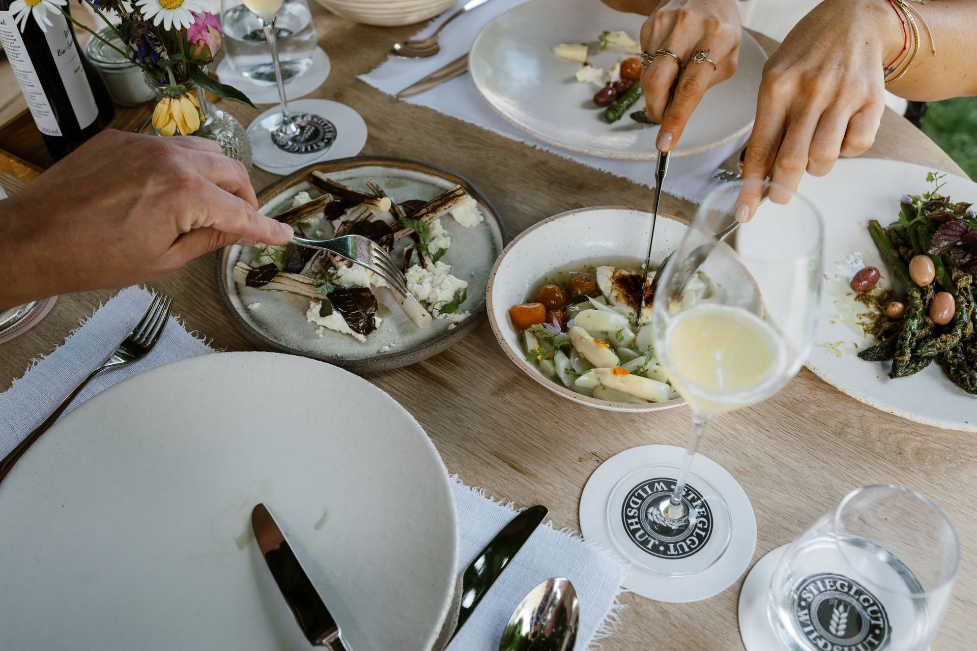A dining table with plates of food, a wine glass, and a water glass.