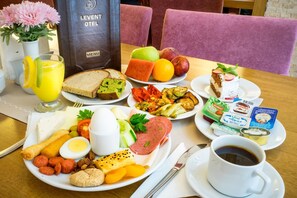 Un buffet de petit-déjeuner avec divers plats, un présentoir à menus et une tasse de café sur une table.