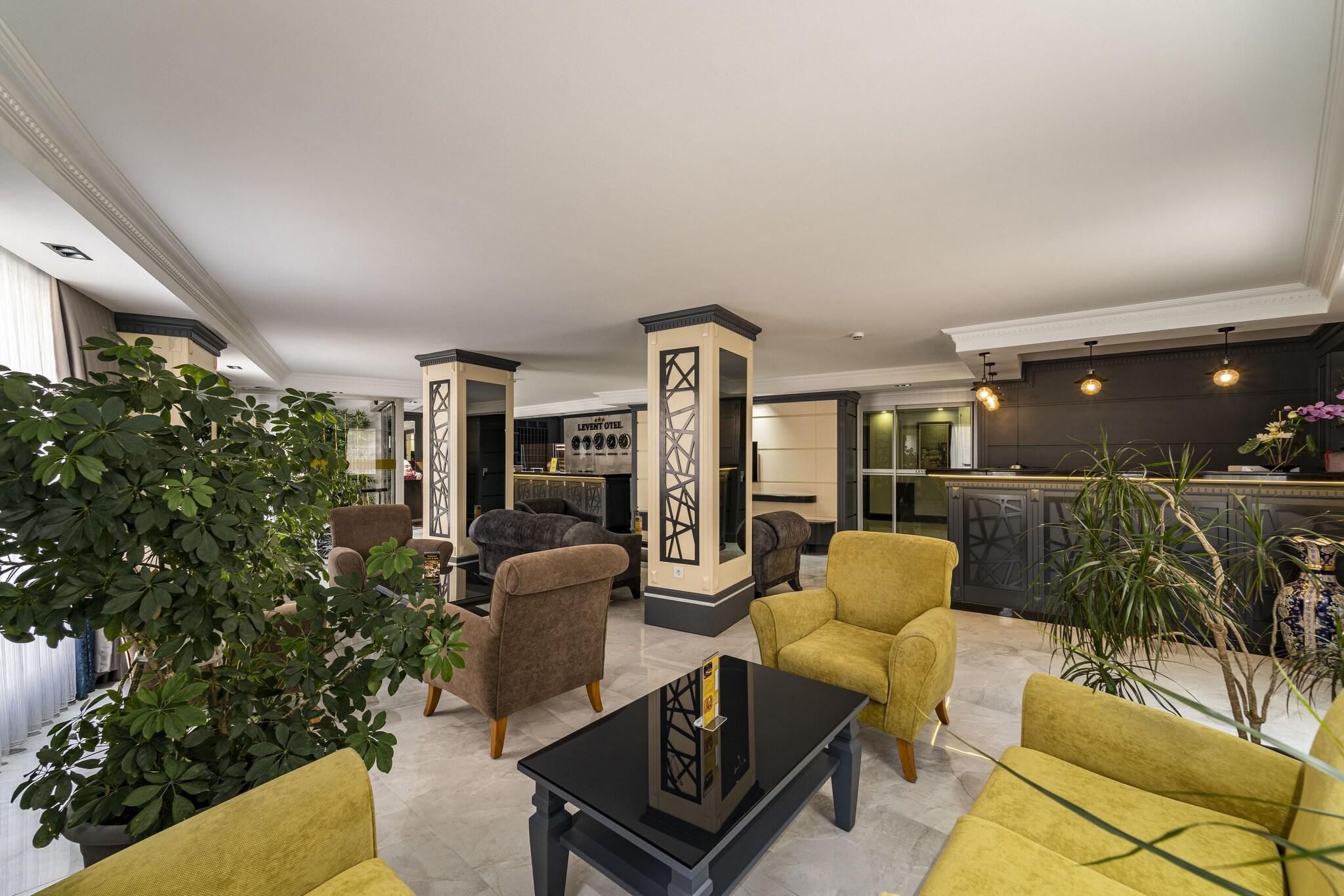 A modern hotel lobby with a seating area, a bar, and a kitchen in the background.