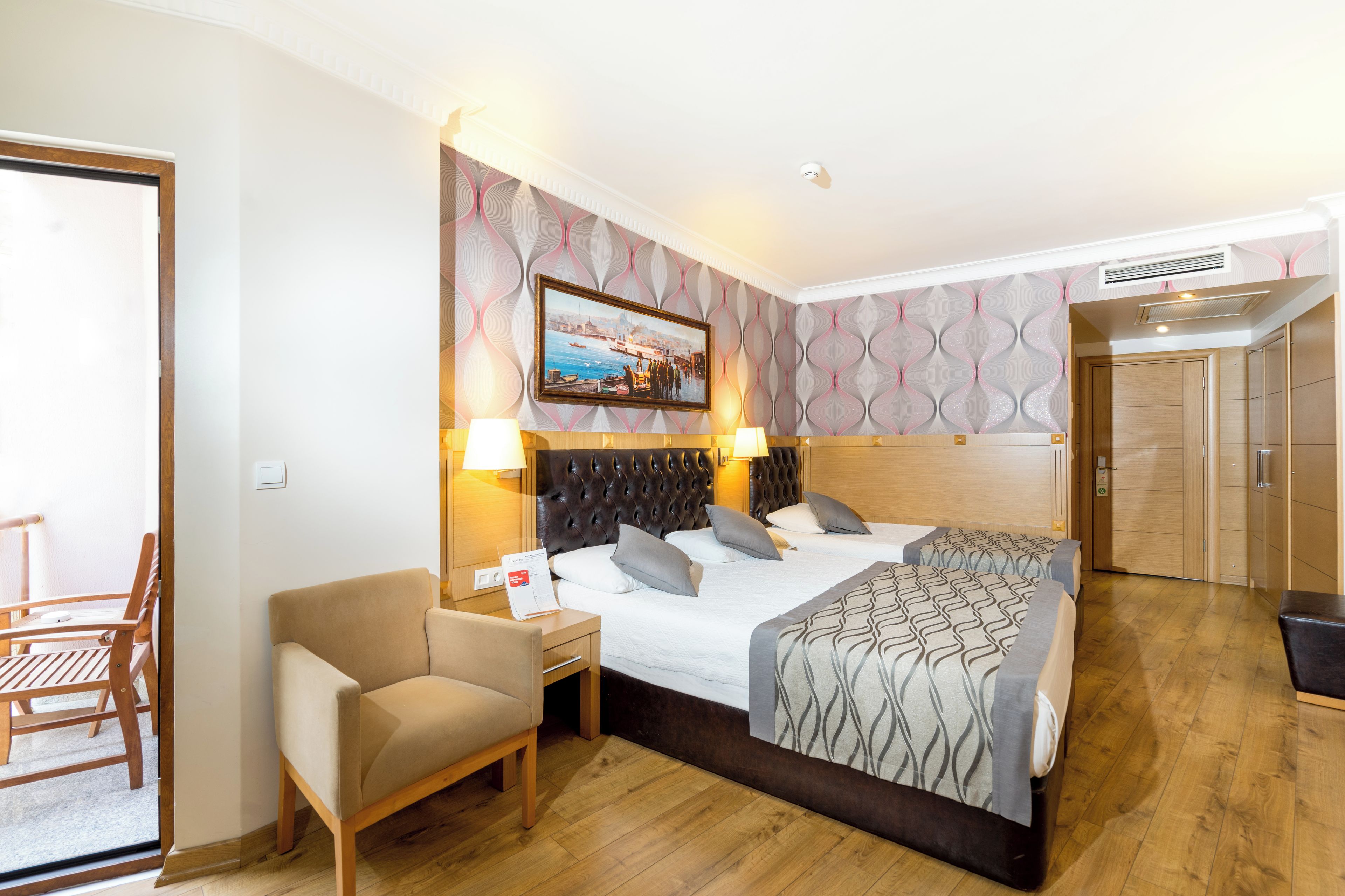 A hotel room with a bed, a chair, a desk, and a door.