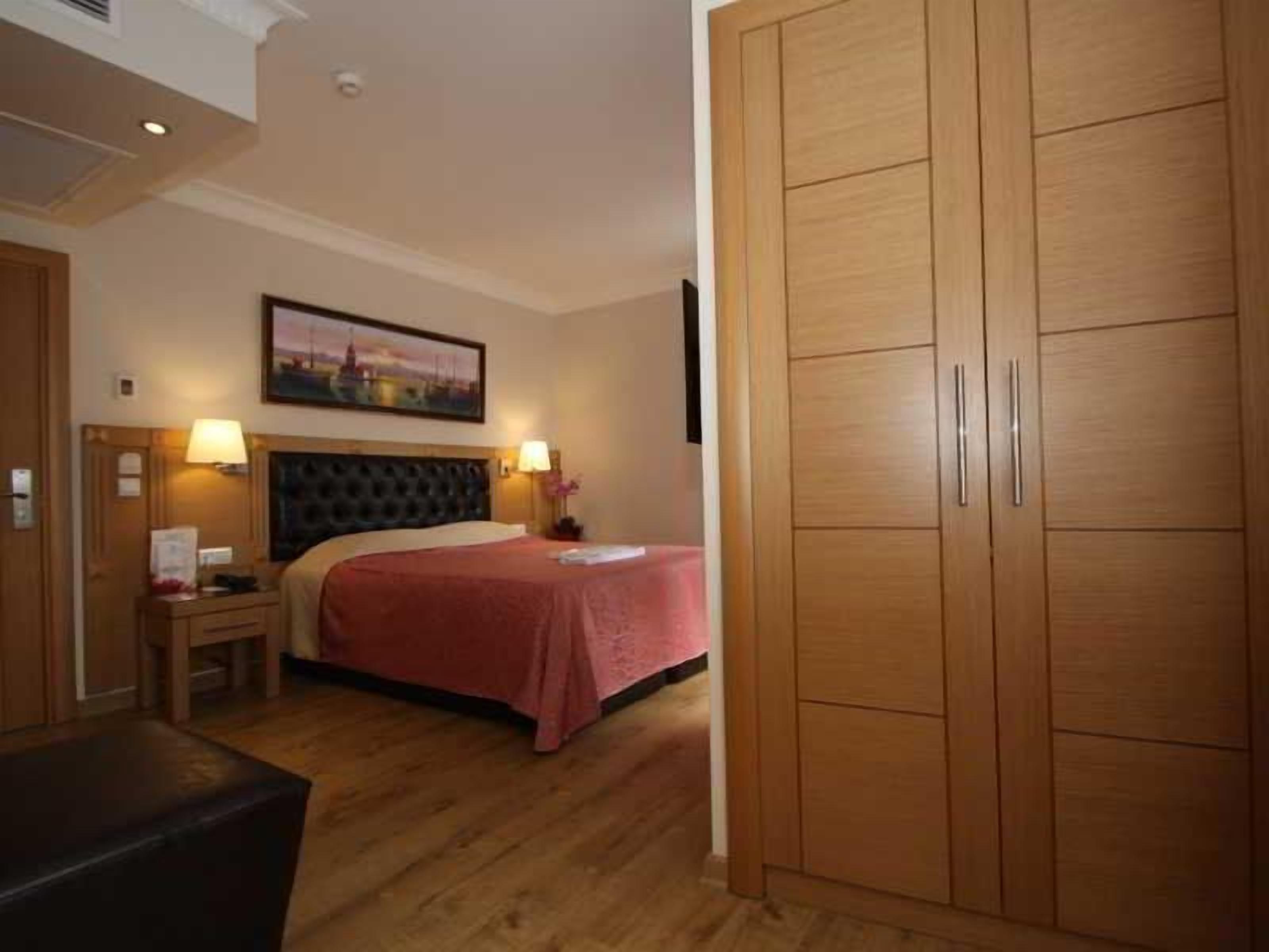 Habitación de hotel con cama, mesitas de noche, armario de madera y un cuadro en la pared.