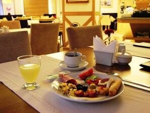 Ein Esstisch mit einem Teller Essen, einer Kaffeetasse und einem Glas Saft.